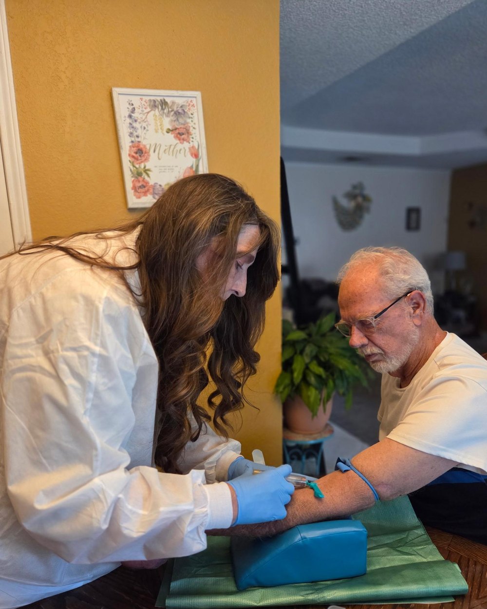 Mary Bratcher performing a blood draw for a seated patient during a home visit